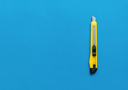 A thin yellow paper knife on a bright blue background. minimalist concept.の写真素材