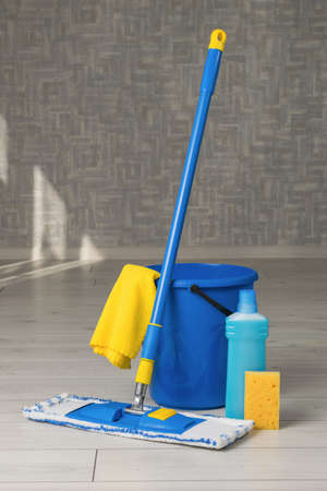 A bucket with accessories for cleaning rooms on a wooden floor. Home and office cleaning kit. The concept of maintaining cleanliness. flat lay.の写真素材