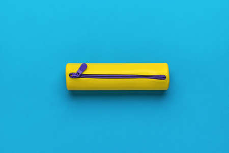 Yellow pencil case for pencils and pens on a blue background. The minimum concept of storing school...