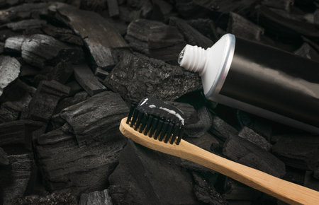 A bamboo toothbrush and a tube of gel paste on a charcoal background. Teeth whitening and dental care products.の写真素材