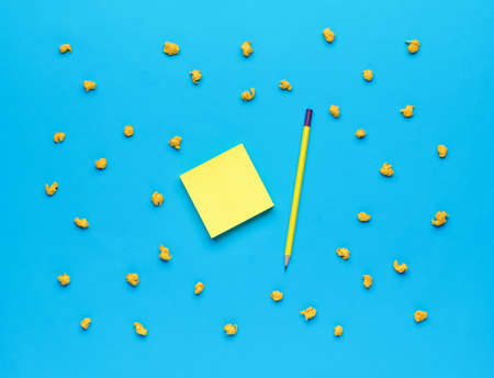 Minimal business concept. A stack of note paper, a pencil and pieces of crumpled paper on a blue...