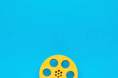 Yellow plastic film reel on a blue background. The minimal concept of cinema. flat lay.の写真素材