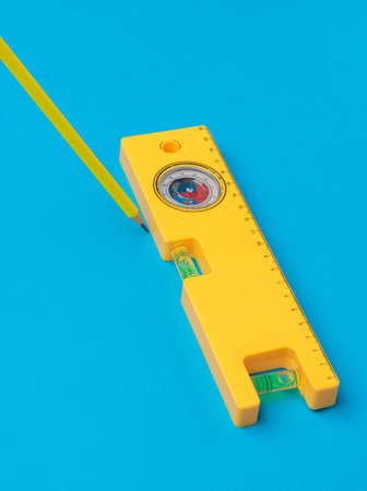 Yellow building level and yellow pencil on a blue background. Minimal concept of construction and repair.の写真素材