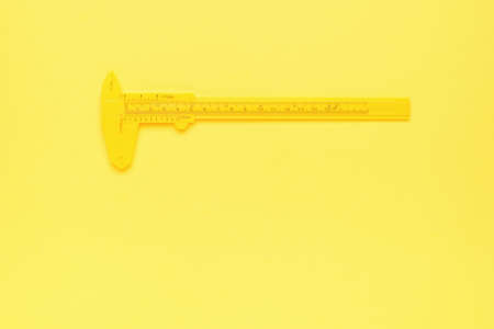 Yellow caliper on a yellow background. Monochrome image of the instrument. A tool for accurate...