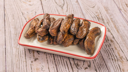Ceramic white cup with dried bananas on a wooden table. Delicious natural fruit snack.の写真素材