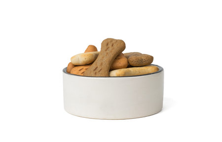 Ceramic bowl filled with cookies for dogs isolated on a white background. A delicious treat for dogs with cereals.の写真素材