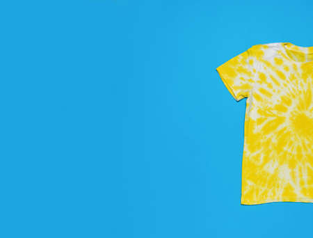 Half of a tie dye T-shirt on a blue background. A place for your text. Minimal fashion concept. flat lay.の写真素材