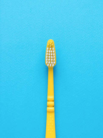 A bright yellow toothbrush on a blue background. Minimal oral care concept. flat lay.の写真素材
