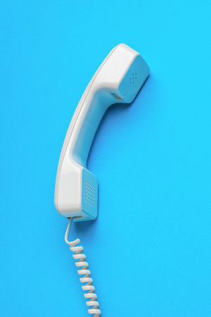 Classic handset with a wire on a blue background. Minimal concept of communication organization.の写真素材