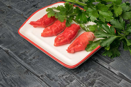 Bright red crab claws with lots of parsley in a plate on a wooden table. A delicious seafood dish.