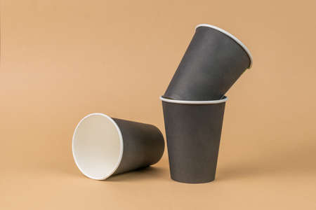 Three dark paper cups on a light brown background. minimal concept. Drinks to take away.の写真素材