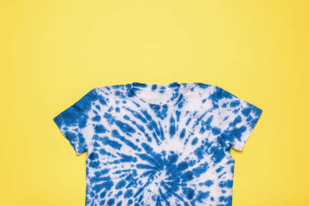 Blue tie dye T-shirt on a yellow background. Minimal fashion concept. flat lay.の写真素材