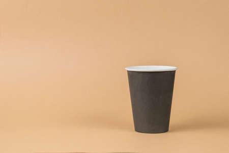 A dark colored paper coffee cup on a light beige background. minimal concept. Drinks to take away.の写真素材