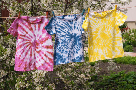 Drying three multi-colored T-shirts in tie dye style. Minimal fashion concept.の写真素材