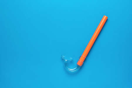 Orange snorkel on a blue background. Minimal concept of summer recreation and scuba diving. flat lay.の写真素材