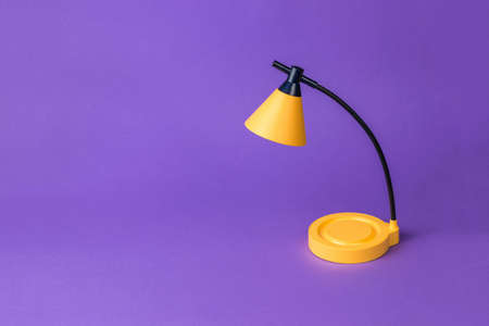 A yellow table lamp on a dark purple background. desktop lighting.の写真素材