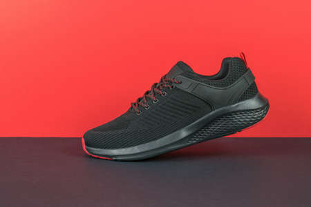 A walking black sneaker on a black and red background. Minimal sports concept. flat lay.の写真素材