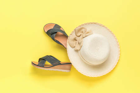 A large women's hat and summer mesh shoes on a yellow background.The minimum concept of summer holidays. flat lay.の写真素材