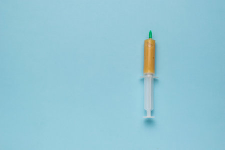 A plastic syringe with an insect repellent on a blue background. Minimal concept of pest control. flat lay.の写真素材