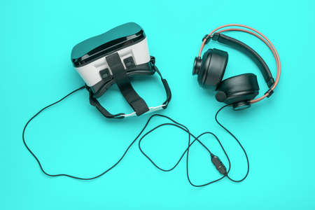 VR glasses and headphones on a light green background. A popular virtual reality gadget. flat lay.の写真素材