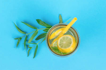 Top view of a glass of water with lemon and mint on a blue background. A popular refreshing drink. flat lay.の写真素材