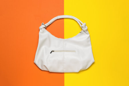 A large beautiful white leather women's bag on a yellow and orange background. Women's Accessory. flat lay.の写真素材