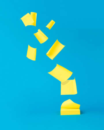 Flying yellow note paper on a blue background. Minimal concept of office supplies. office supplies.の写真素材