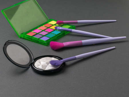 Highlighter and multi-colored eye shadow with brushes on a gray background. The concept of women's makeup.の写真素材