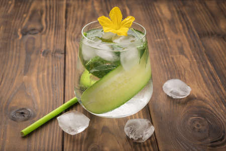 A drink of cucumbers, water and flowers on a wooden table. A natural cooling drink.の写真素材