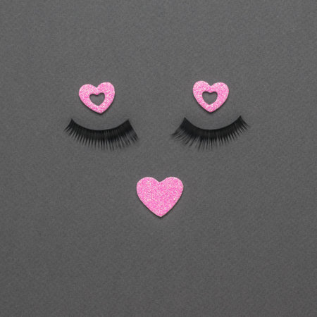 A face made of eyelashes and pink hearts on a gray background. The concept of female beauty. flat lay.の写真素材