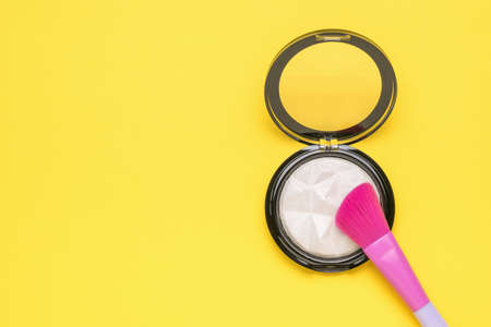 A bright brush and a jar with a highlighter on a yellow background. Minimal concept of women's makeup. flat lay.の写真素材