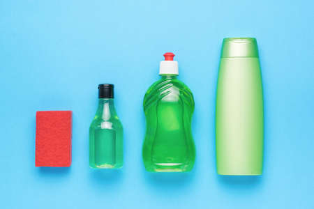 Red foam sponge and green bottles with detergents on a blue background. cleaning kit. flat lay.の写真素材