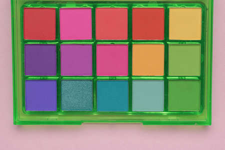 A set of multi-colored eyeshadow in a green package on a pink background. The concept of women's makeup. flat lay.の写真素材