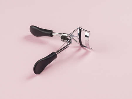 Eyelash curlers on a light pink background. Minimal makeup concept.の写真素材