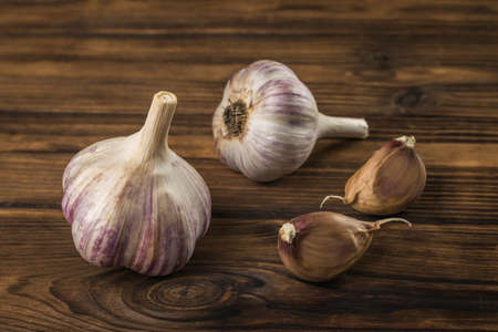 Two cloves of garlic and two heads of garlic on a wooden table. natural spices and seasonings.