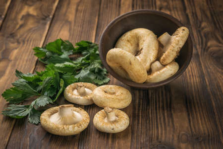 Forest mushrooms spilling out of the bowl on a wooden background. Vegetarian food from the forest.の写真素材