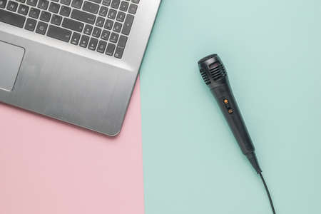 Microphone with a wire near the laptop on a blue and pink background. The concept of a freelancer's...