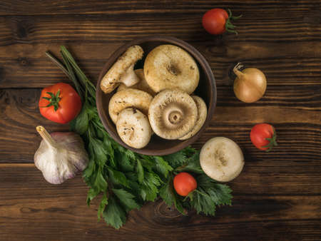 Forest mushrooms with vegetables and herbs on a wooden background. Vegetarian food from the forest. flat lay.の写真素材