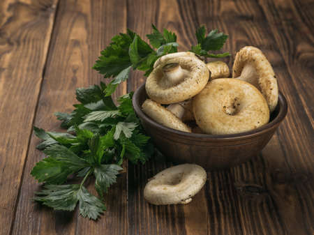 A large bowl with large mushrooms and parsley leaves on a wooden table. Vegetarian food from the forest.の写真素材
