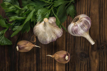 Fresh garlic and parsley leaves on a wooden background. natural spices and seasonings.の写真素材