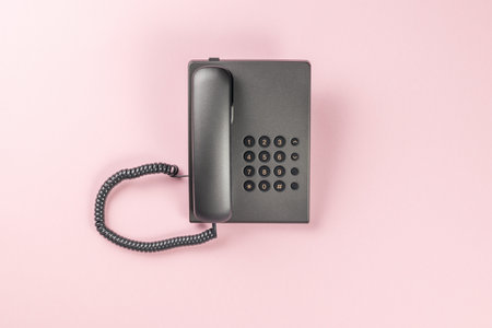 The office telephone is gray on a pink background. The concept of telephone communication. flat lay.