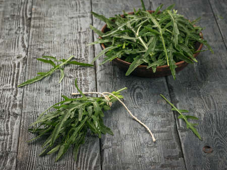 Scattered arugula leaves and a separate bundle lying on a wooden table. Vitamin vegetarian food.の写真素材