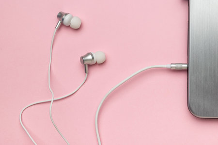 White stylish headphones connected to a laptop on a pink background. The concept of business and education. flat lay.の写真素材