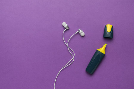 Yellow marker and white headphones on a purple background. The minimum concept of education. flat lay.の写真素材