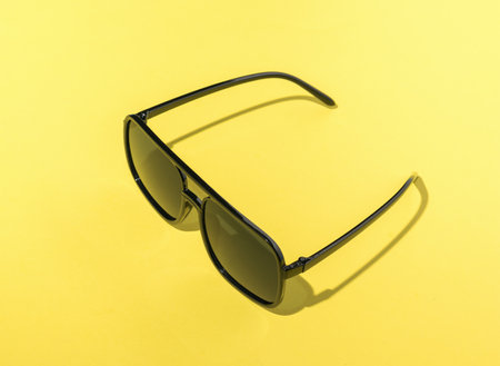 Large sunglasses on a bright yellow background. Stylish summer accessory.の写真素材