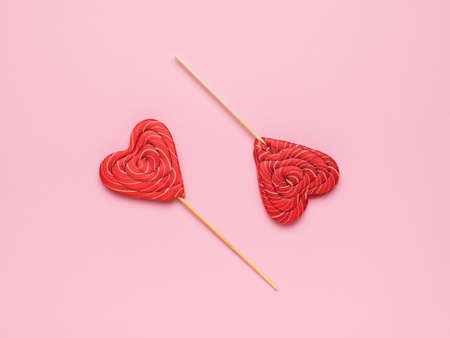 Two red heart-shaped candies on a pink background. Minimal concept of sweet life and love. flat lay.の写真素材