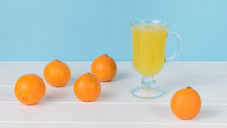 A glass of juice and tangerines scattered on a wooden table. A refreshing drink made of tangerines.の写真素材