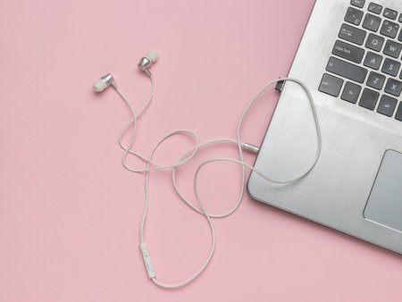 Stylish headphones connected to a laptop on a pink background. The concept of business and education. flat lay.の写真素材