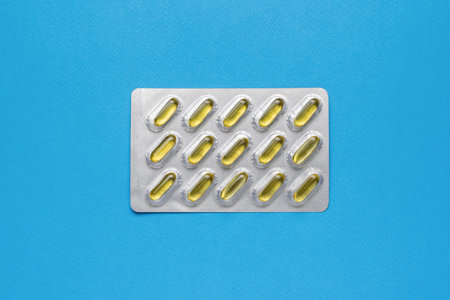 A shiny package with fish oil capsules on a blue background. Biologically active additive. flat lay.の写真素材