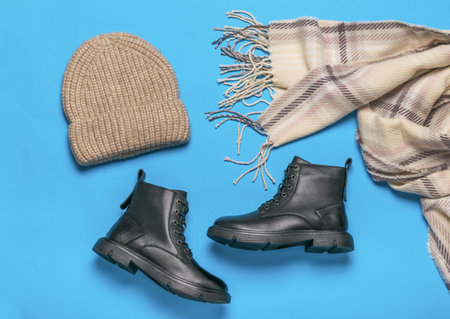 Knitted hat, scarf and a pair of shoes on a blue background. Casual stylish shoes. flat lay.の写真素材